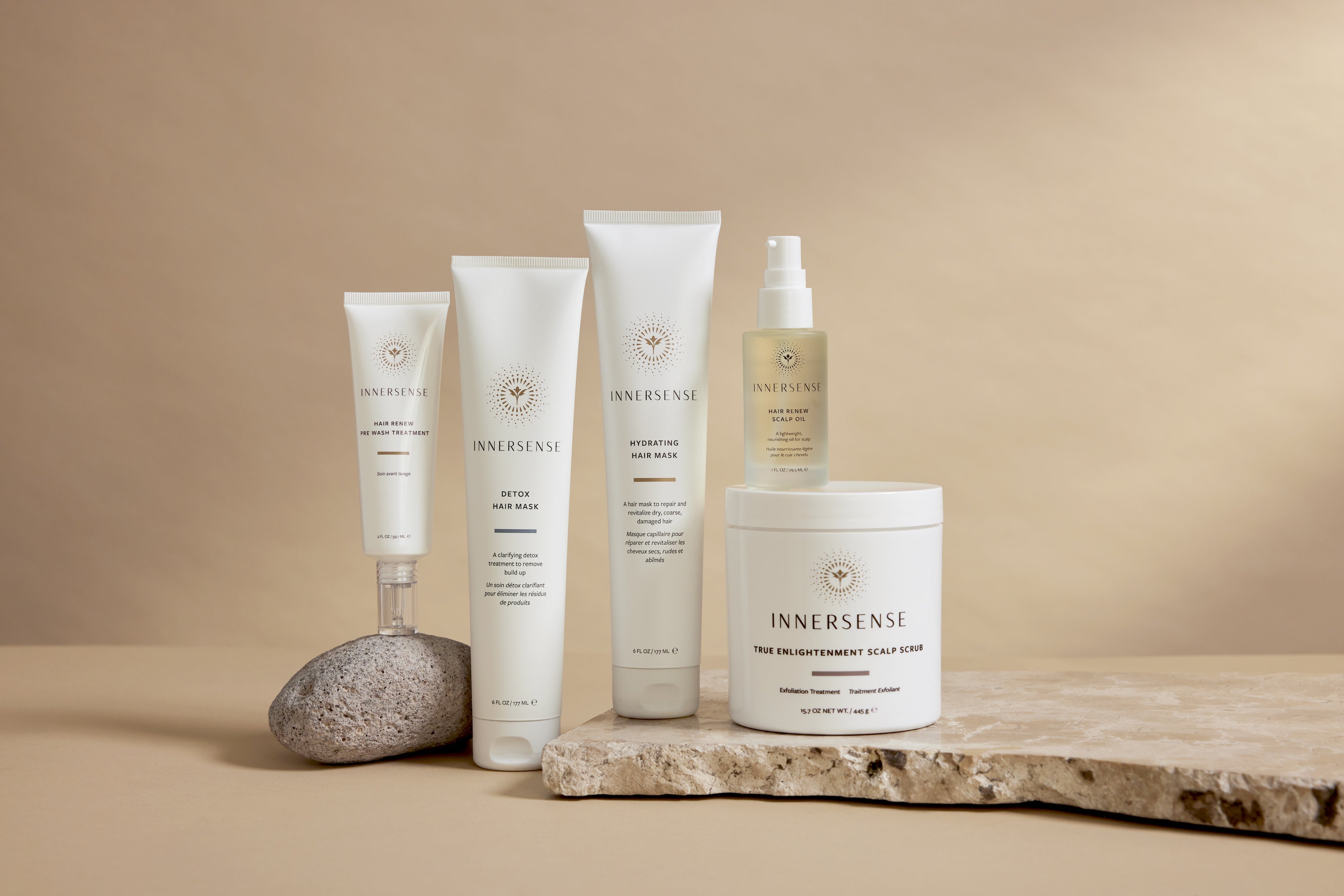 3 Innersense Produktflaschen liegen nebeneinander zwischen aufgeschnittener Avocado und Blütenblättern.