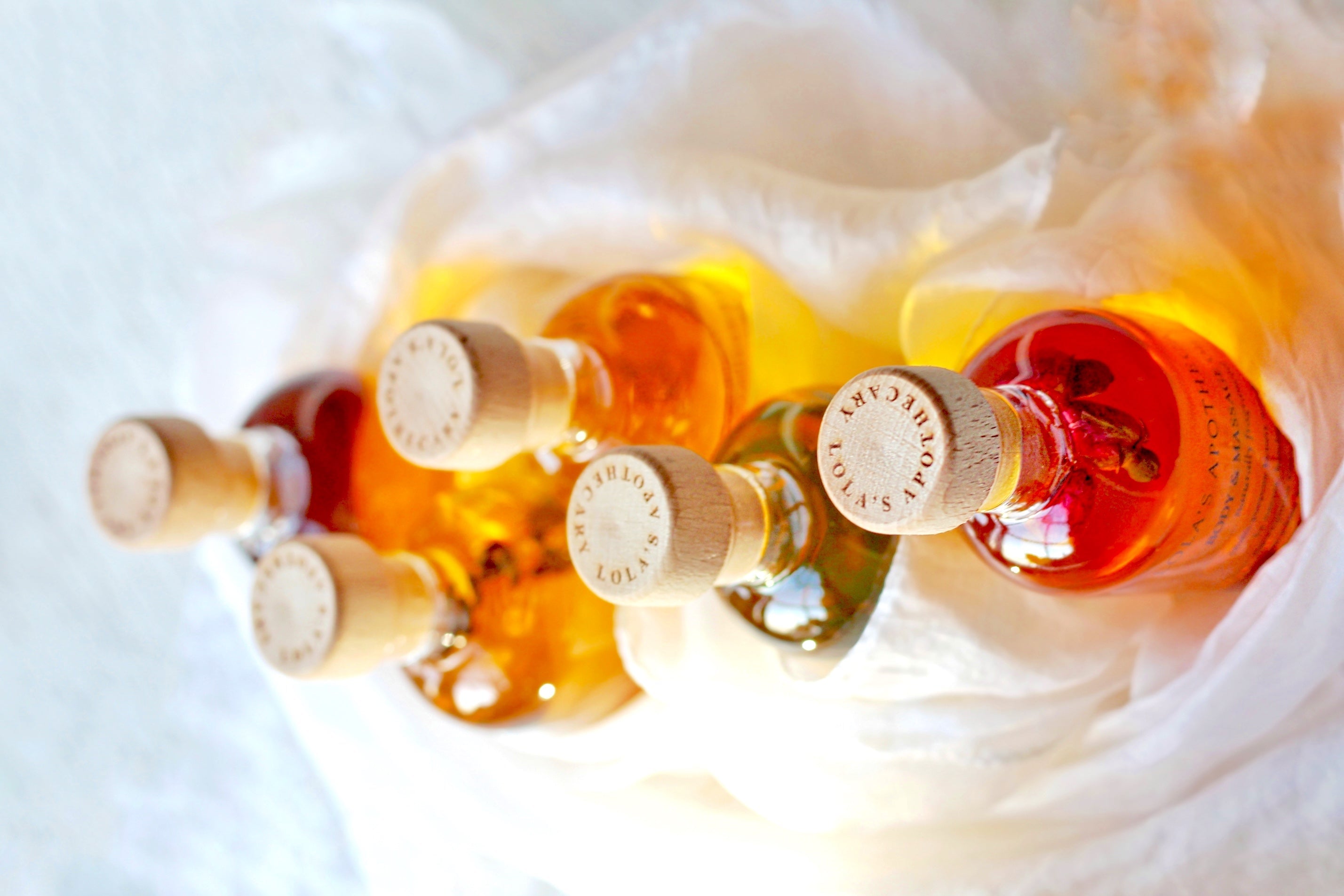 6 verschiedene Massage- & Bodyoil Flaschen stehen im Schnee auf einer Steinplatte.