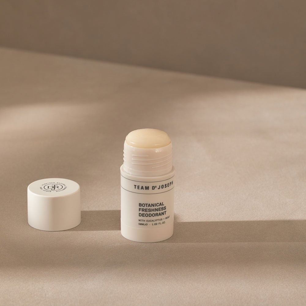 Geöffneter Team Dr Joseph Daily Comfort Deodorant – Stick mit abgenommenem Deckel, zeigt die feste, naturfarbene Deocreme in runder Form, minimalistische Verpackung in Beige mit schwarzem Schriftzug.