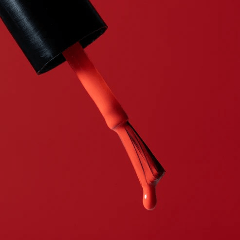 Pinsel mit tropfenden leuchtend rotem Nagellack von Karolin Van Loon – Farbton Rouge Solaire