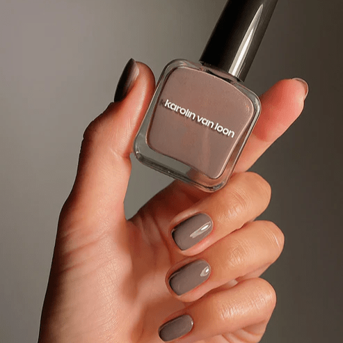 Taupefarbener Nagellack mit Schimmer – Karolin Van Loon Taupe Lustré in 15-ml-Flasche von gepflegter Hand gehalten.
