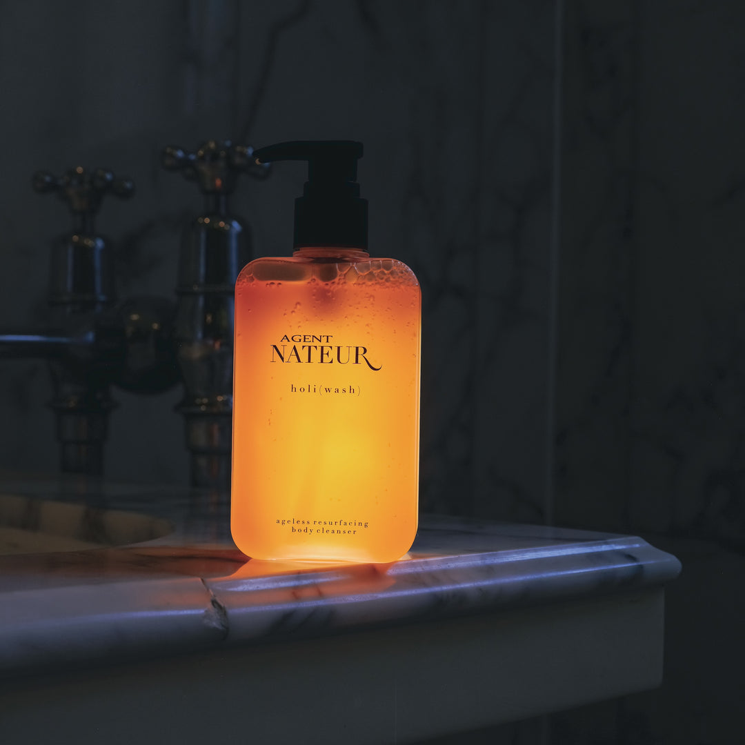 Agent Nateur holi (wash) Flasche steht im abgedunkeltem Badezimmer auf dem Badewannenrand, leuchtet hell. North Glow