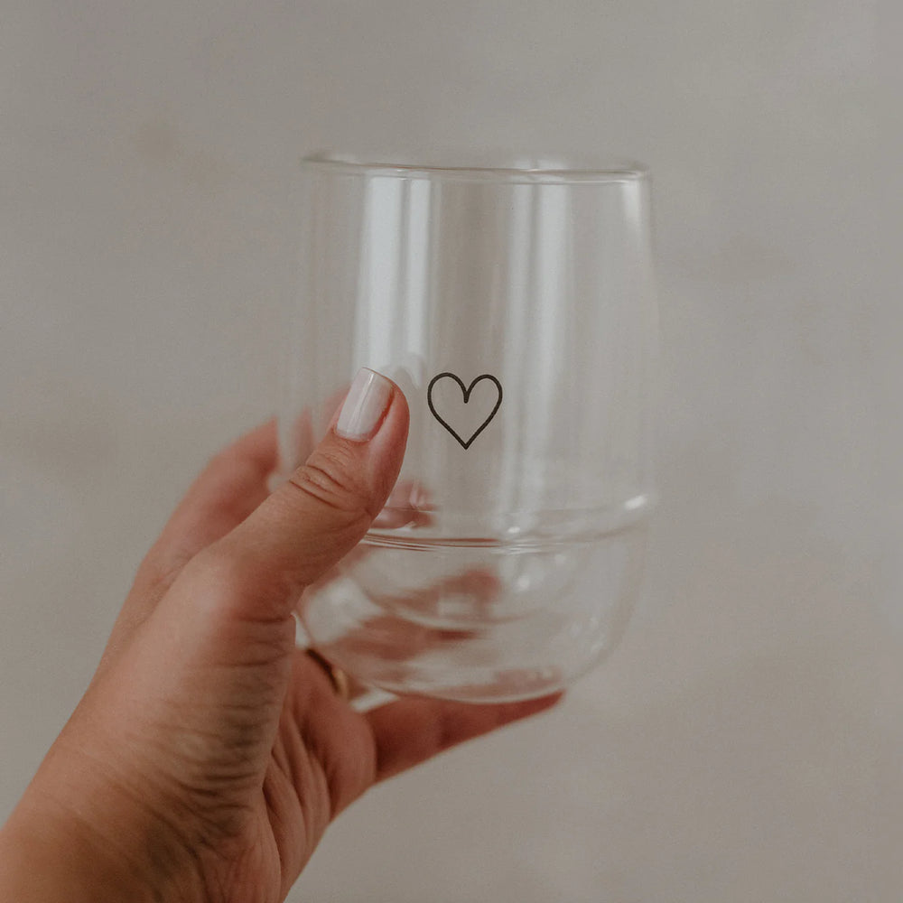 Doppelwandiges Latte Macchiato Glas mit Herz von Eulenschnitt wird von einer Hand gehalten.