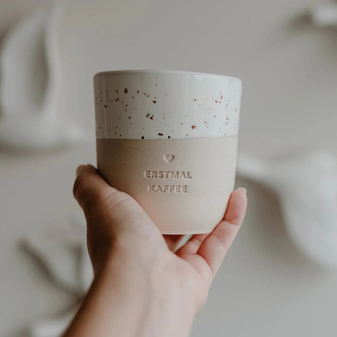Kaffeetasse mit Prägung "Erstmal Kaffee" von Eulenschnitt wird in einer Hand gehalten.