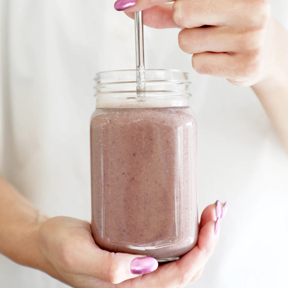 Trinkglas mit Berry Fuel Milchshake wird in einer Hand gehalten