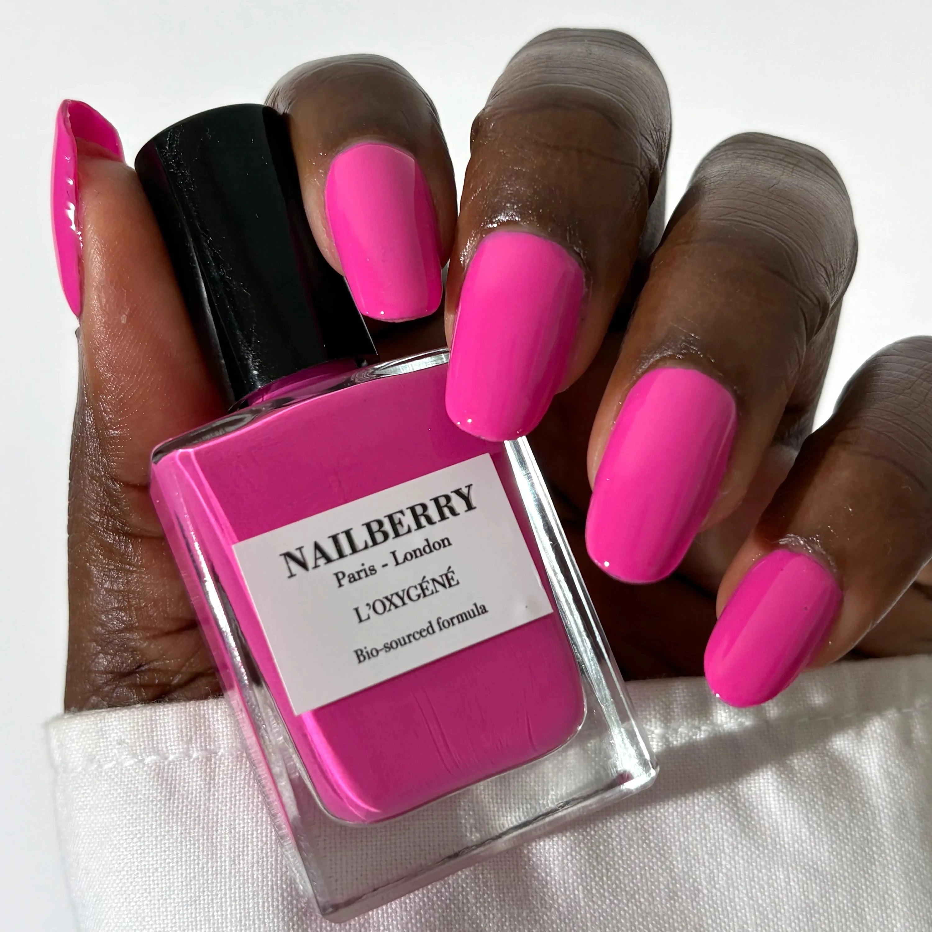 Nailberry Electric Pink Flakon und lackierte Nägel.