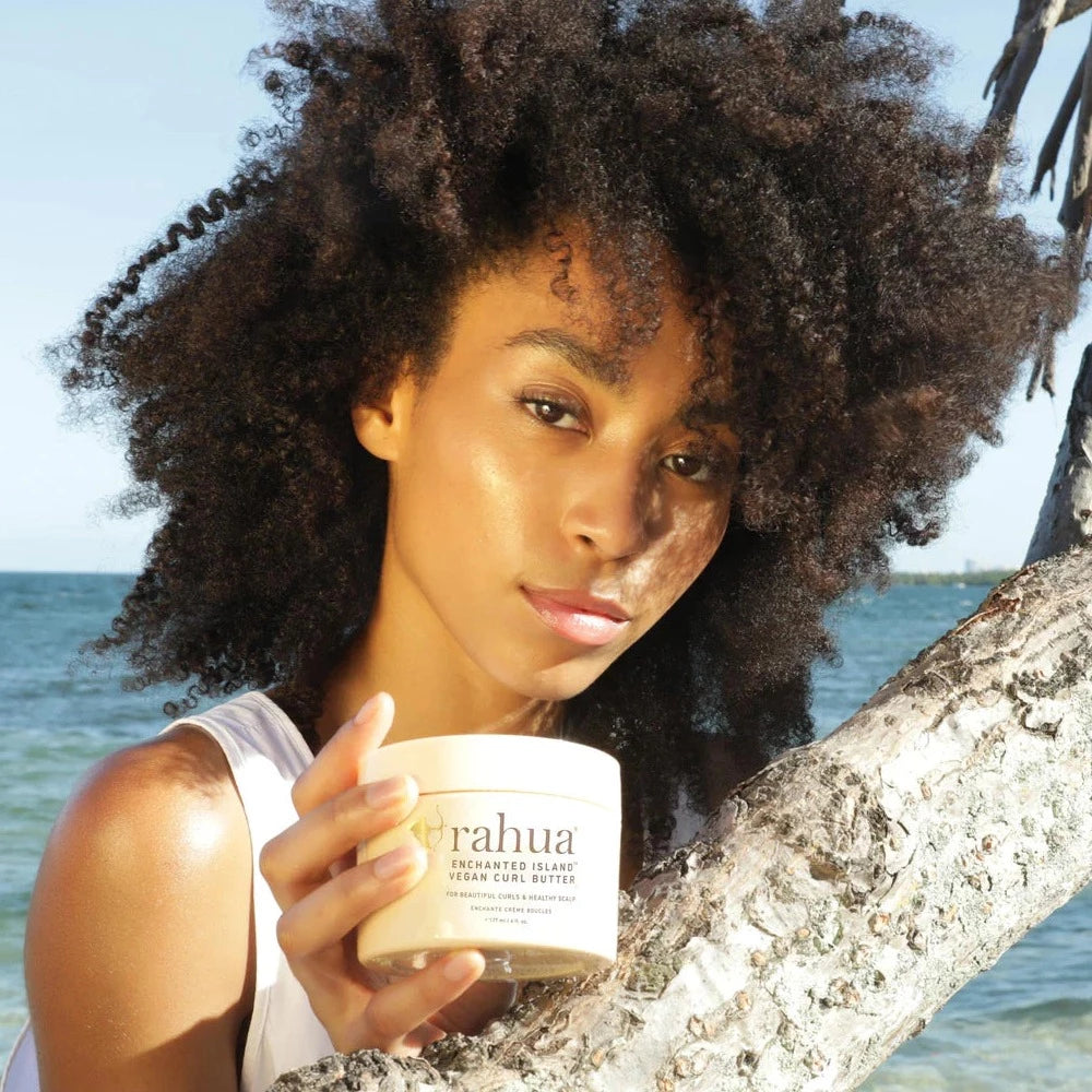 Rahua Enchanted Island Vegan Curl Butter Tiegel wird von weiblichem Model am Strand präsentiert North Glow