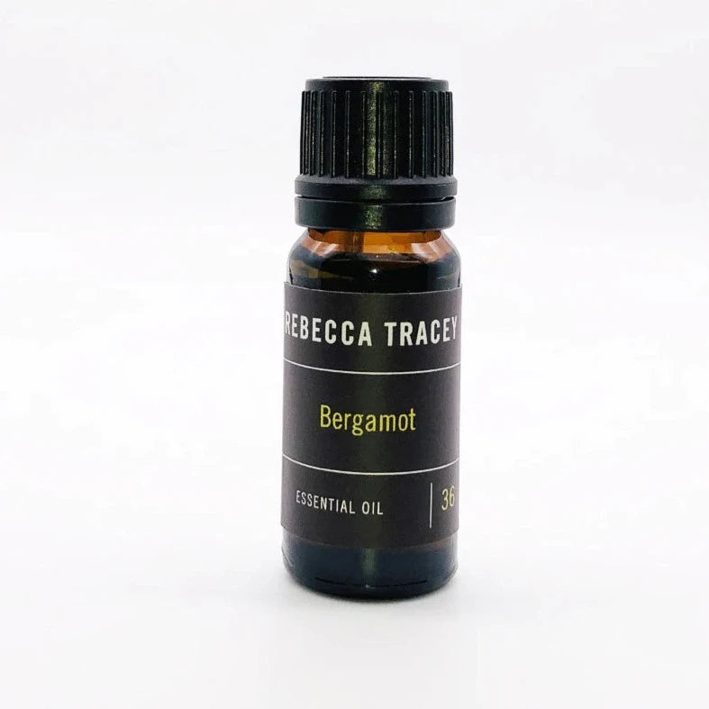 Kleine dunkelbraune Glasflasche "Essential Oil - Bergamot" von Rebecca Tracey vor weißem Hintergrund. North Glow