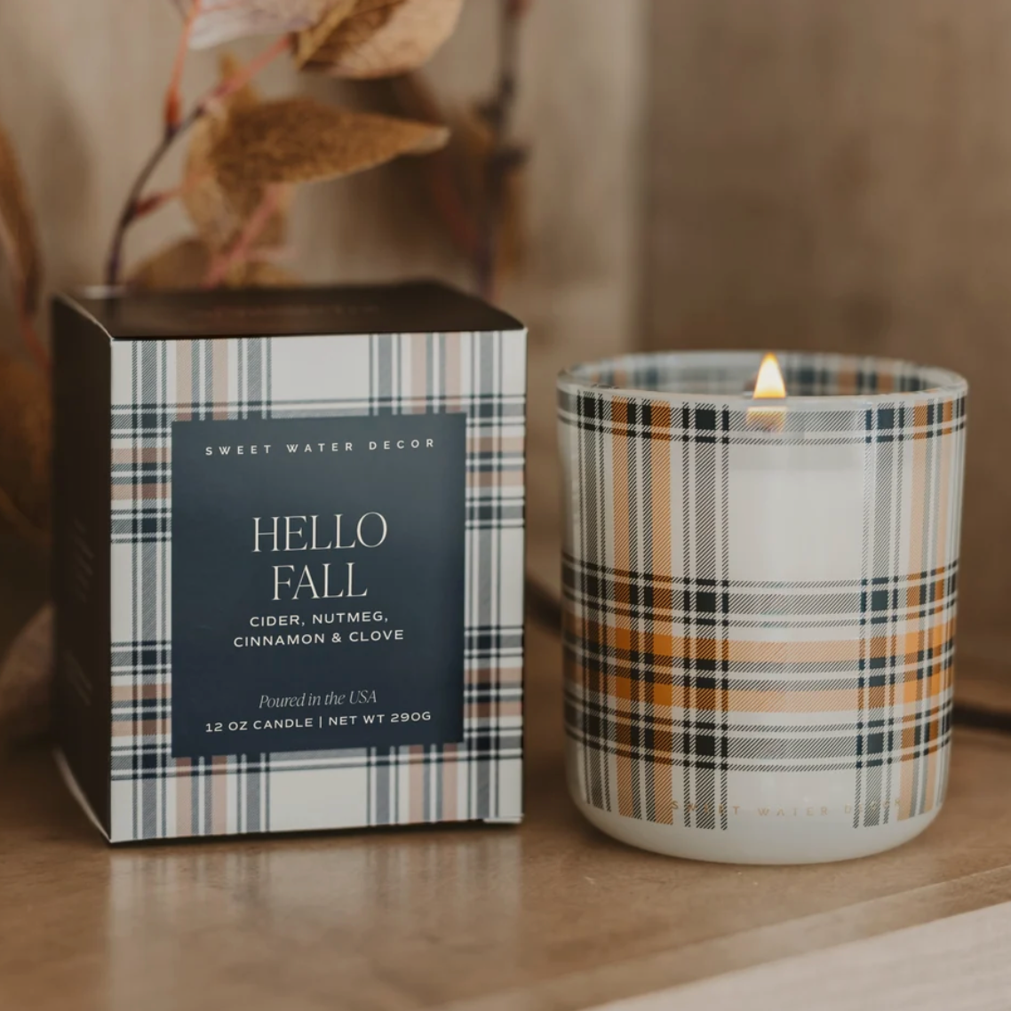Hello Fall - Duftkerze mit Karomuster – neben Produktverpackung.