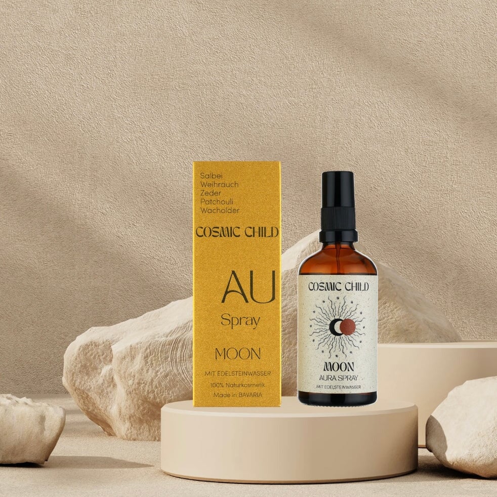 Verpackung und Pumpflasche Aura Spray MOON umgeben von beigen Steinen.
