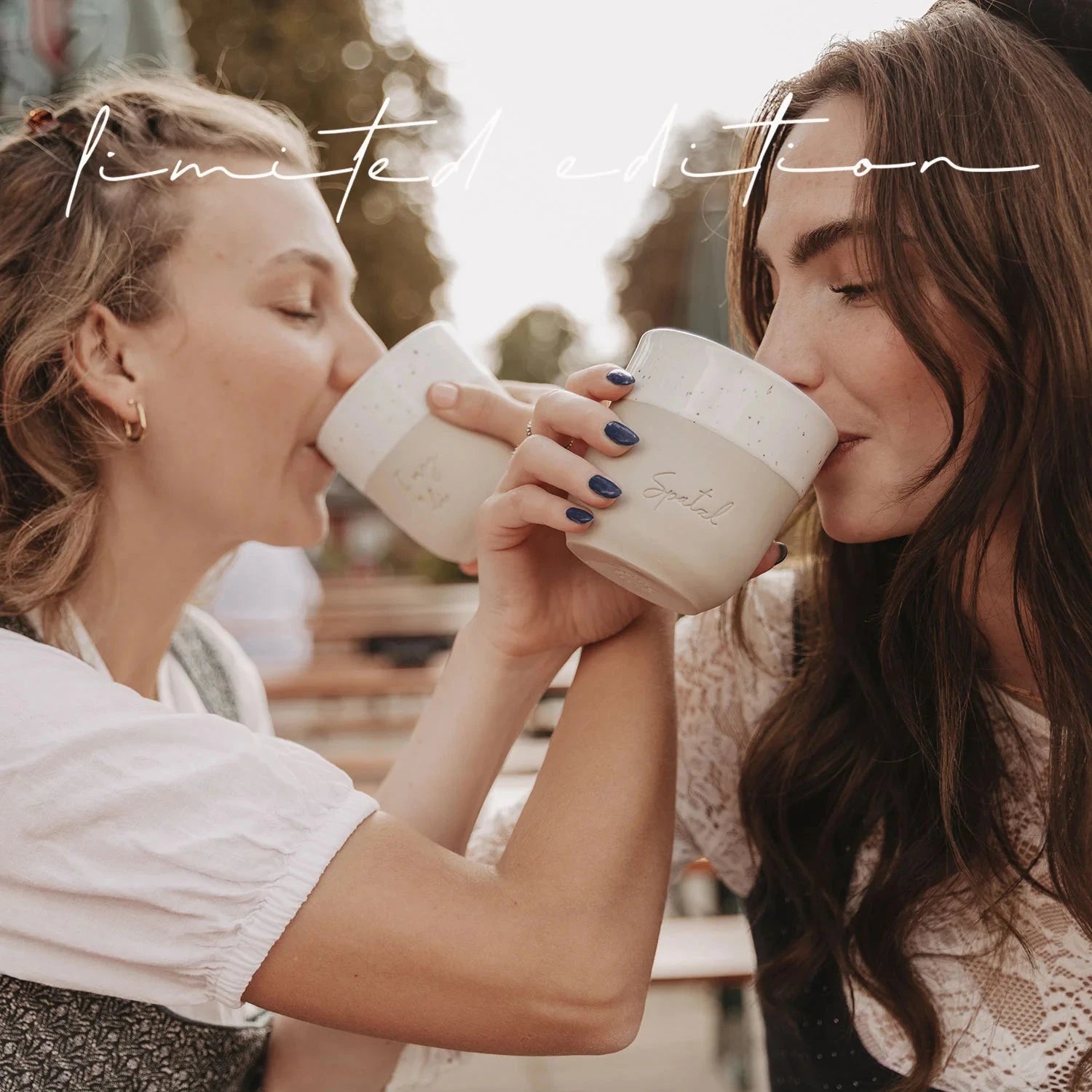 Zwei Frauen trinken aus Eulenschnitt Bechern Spatzl.