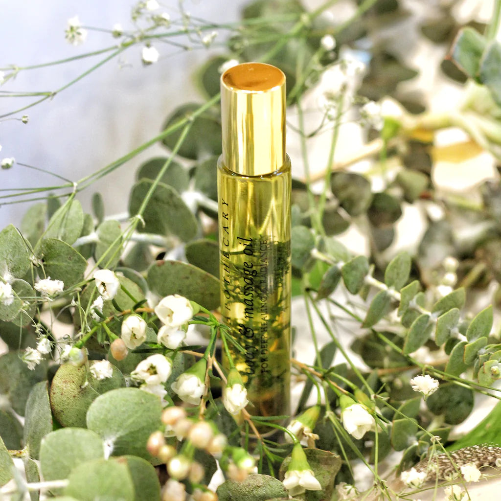 Breath of Clarity body &massage oil von Lola´s Apothecary - Kleine Glasflasche umgeben von grünen Blumen 