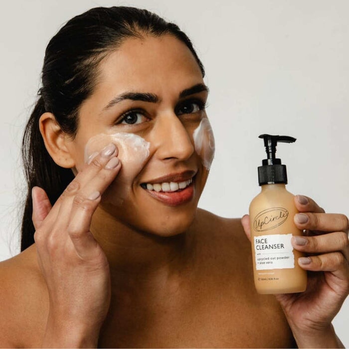 Frau trägt UpCircle Oat Face Cleanser sanft auf das Gesicht auf – natürliche, beruhigende Hautpflege.
