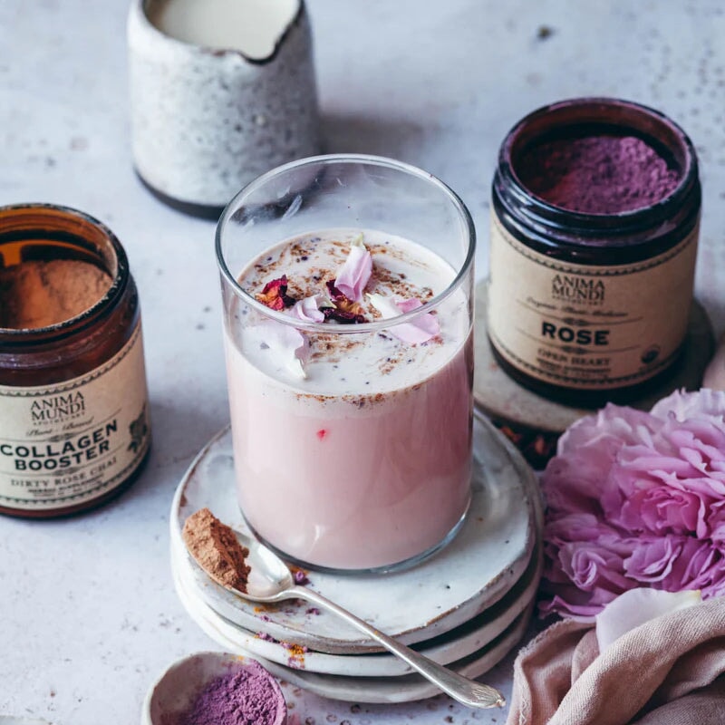 2 offene Anima Mundi Schraubgläser stehen hinter einem Glas mit milchigem Inhalt, dekoriert mit Blütenblättern.