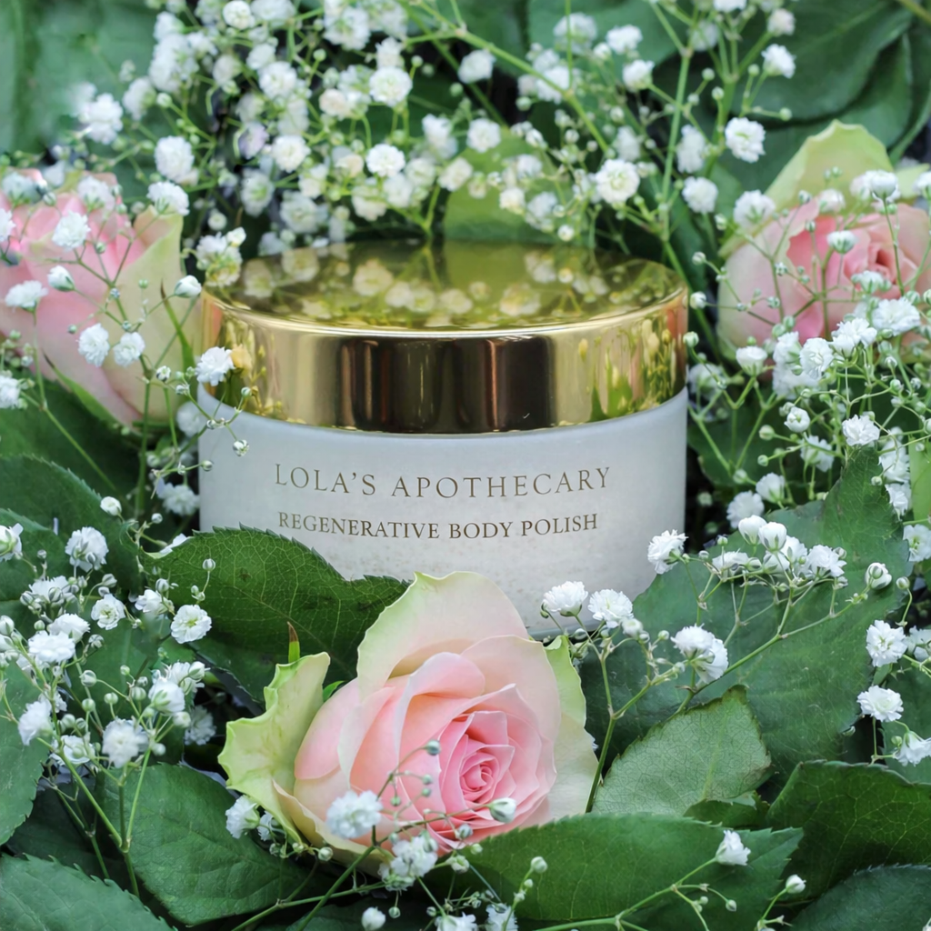 Lola's Apothecary Divine Grace Regenerative Body Polish, umgeben von Rosen.