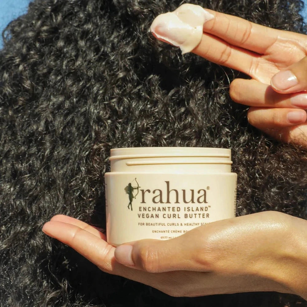 Rahua Enchanted Island Vegan Curl Butter Konsistenz wird von weiblicher Hand an dunkle Locken gehalten