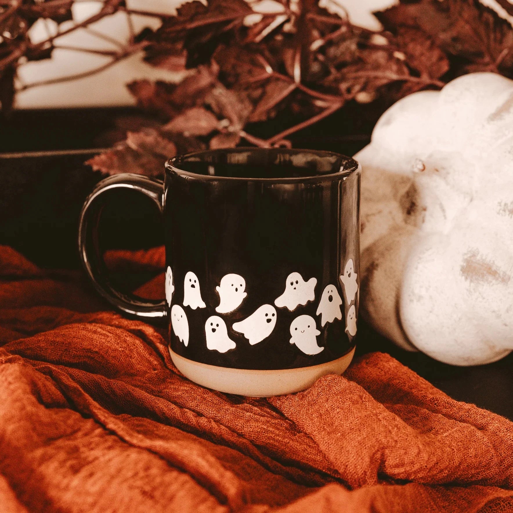 Schwarze Kaffeetasse von Sweet Water Decor mit niedlichen Geistern in herbstlicher Umgebung.