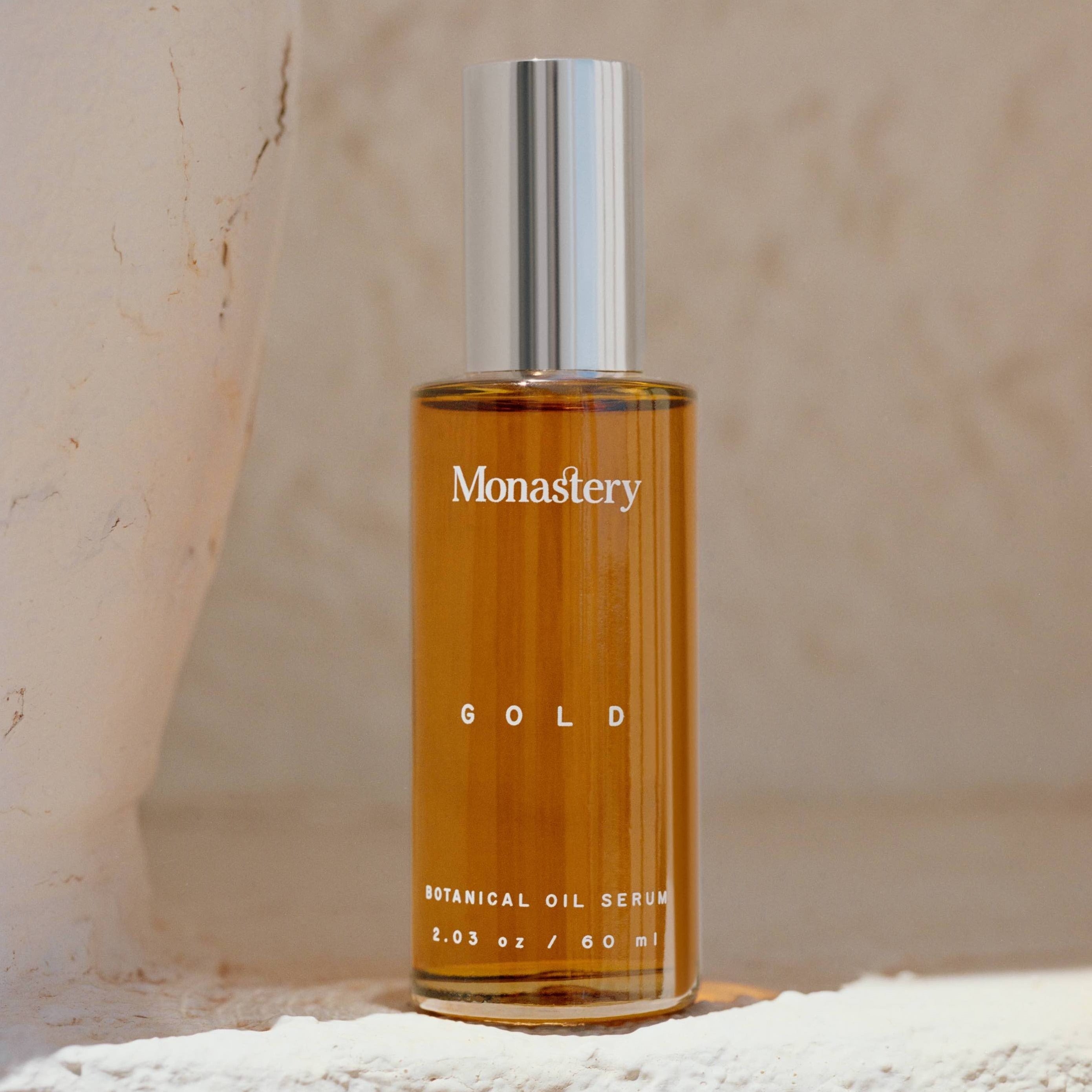 Monastery Gold Serum Glasflasche mit silbernem Deckel steht auf einem Kalkfelsen.