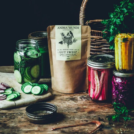 Anima Mundi Gut Sweep – pflanzliches Detox-Pulver umgeben von frischen Kräutern und Gurke