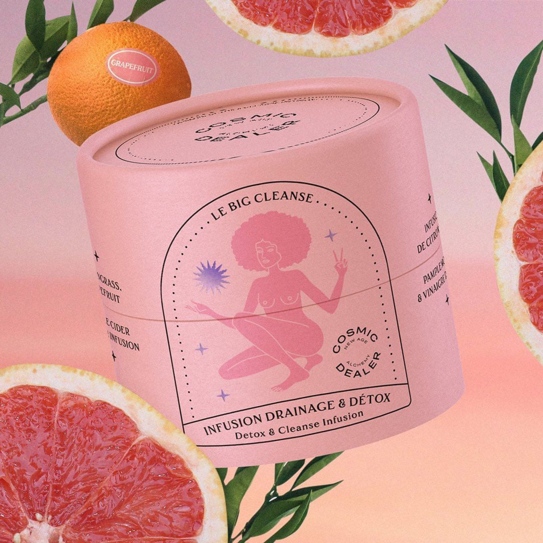 Cosmic Dealer Tee Dose Infusion Drainage & Detox vor rosafarbenem Hintergrund zwischen auf geschnittenen Grapefruithälften..