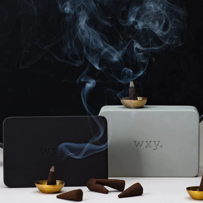 Brennende wxy Oudh Räucherkegel auf strukturiertem Steinuntergrund, natürlich ausgeleuchtet