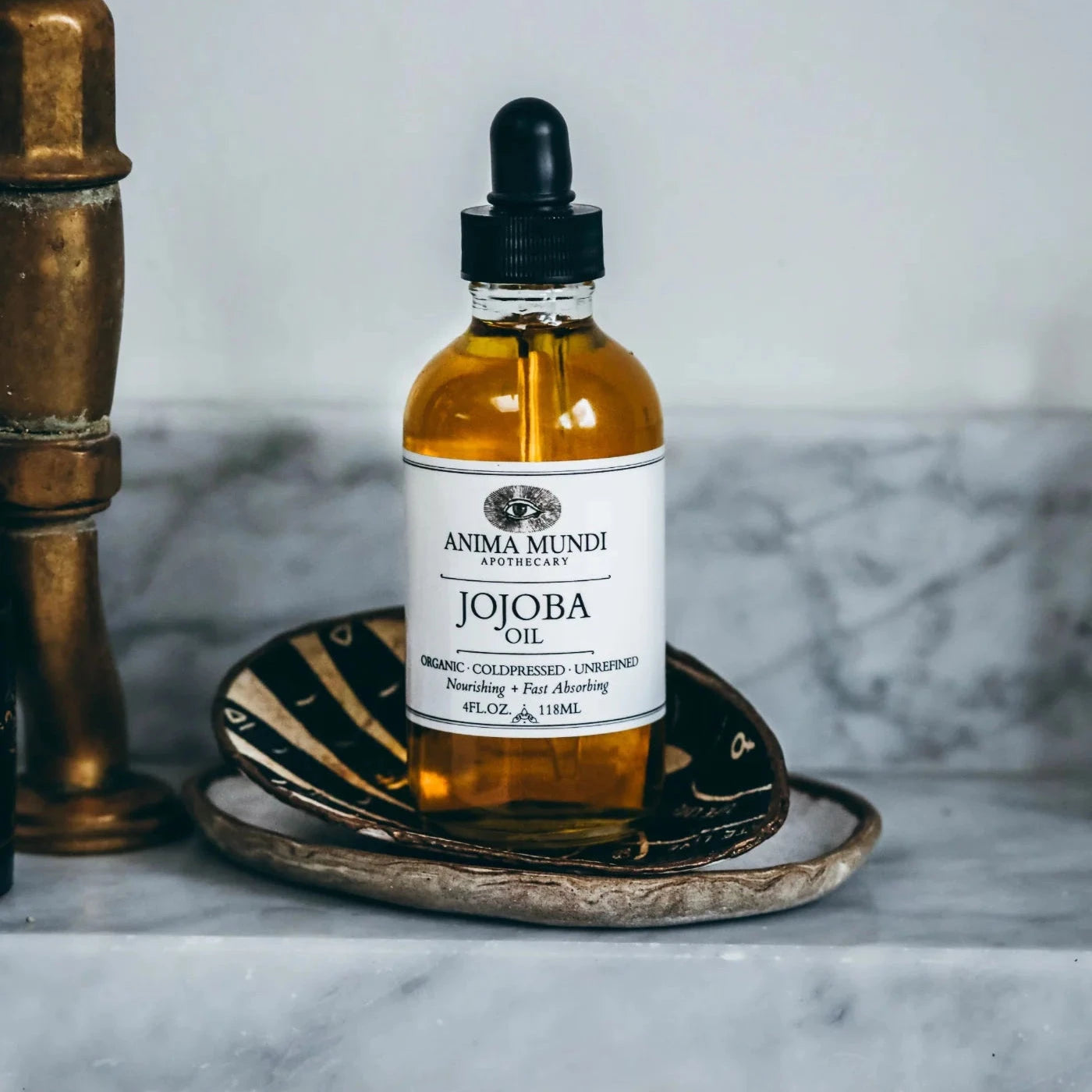 Glasflasche Jojoba Oil von Anima Mundi, stehend in einer Schale.