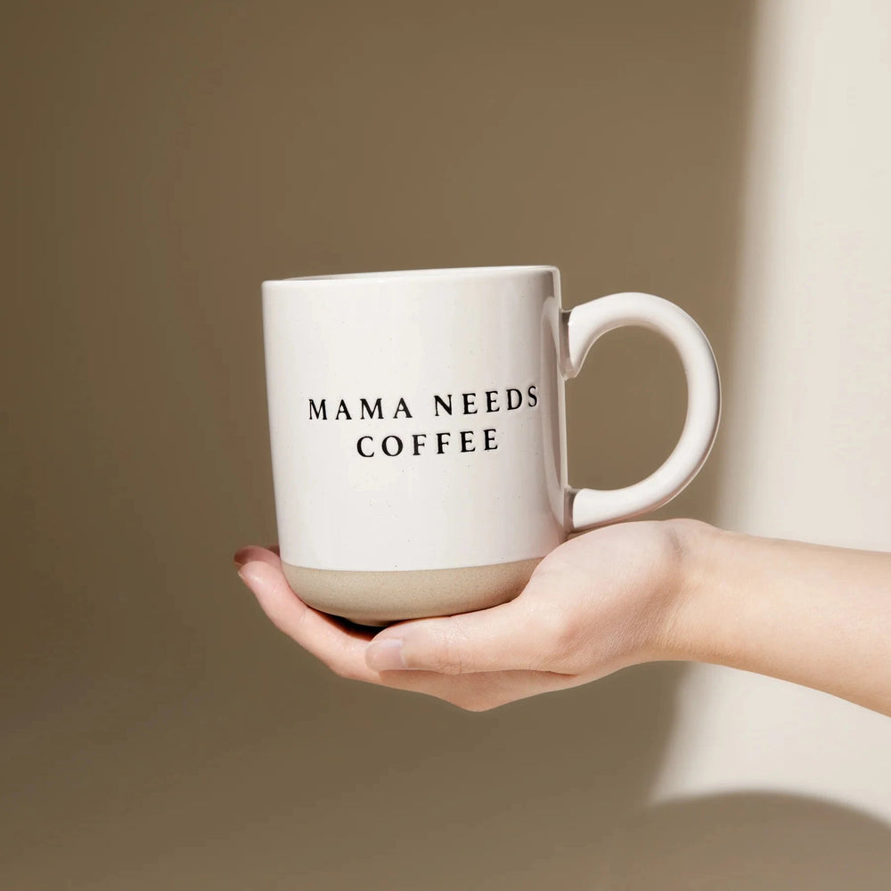 Eine Hand hält einen cremefarbenen Kaffeebecher Mama needs Coffee.