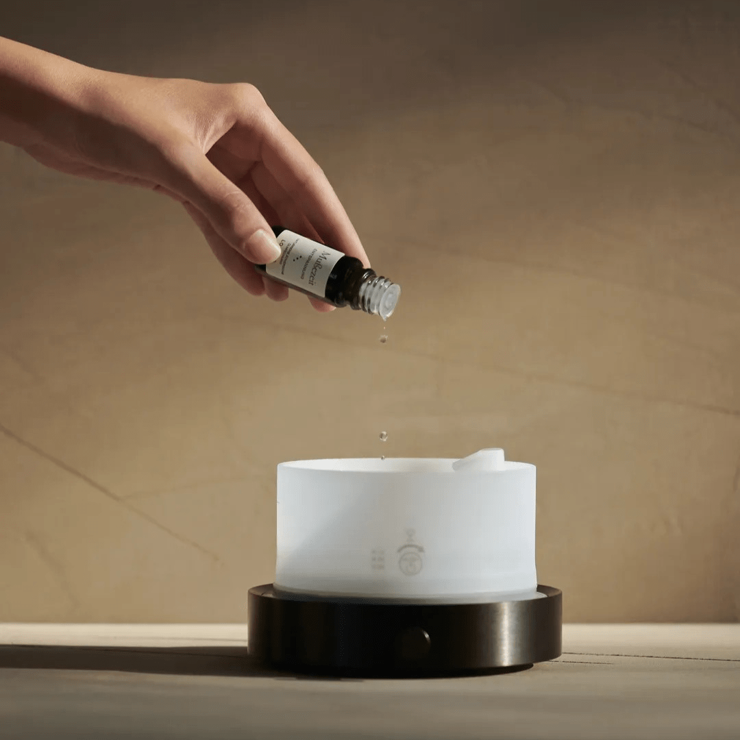 Eine Hand tröpfelt ätherisches Öl in den Looops Diffusor Quint.