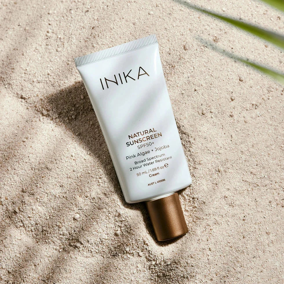 Inika Natural Sunscreen SPF50+ im Sand.
