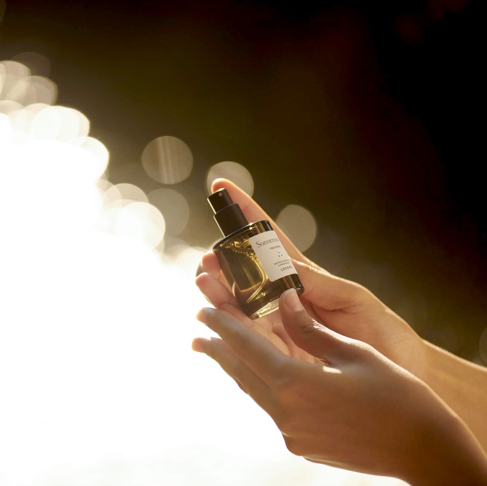 2 Hände halten eine Flasche Raum- und Kissenspray von LOOOPS.