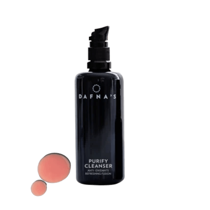 Schwarze Flasche Dafna's Purify Cleanser neben Produktbeispiel vor hellem Hintergrund.