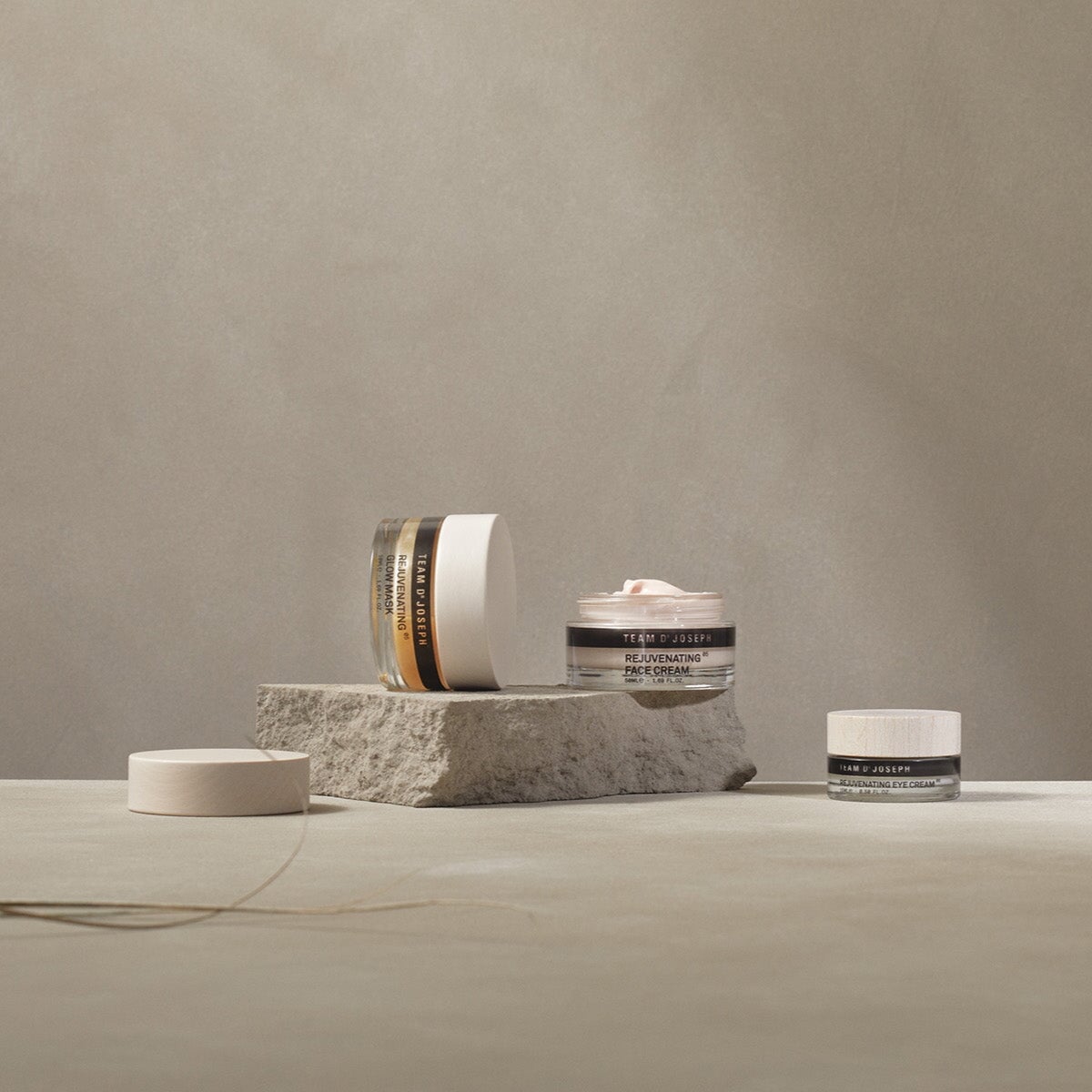 Detailaufnahme eines offenen Kosmetiktiegels mit Rejuvenating Creme von Team Dr Joseph, natürlich in Szene gesetzt auf Stein.