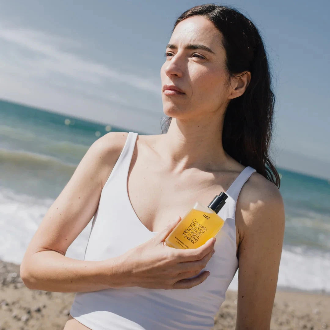 ruhi - The Ceramide Oil Serum Cleanser in der Hand einer Frau am Strand.