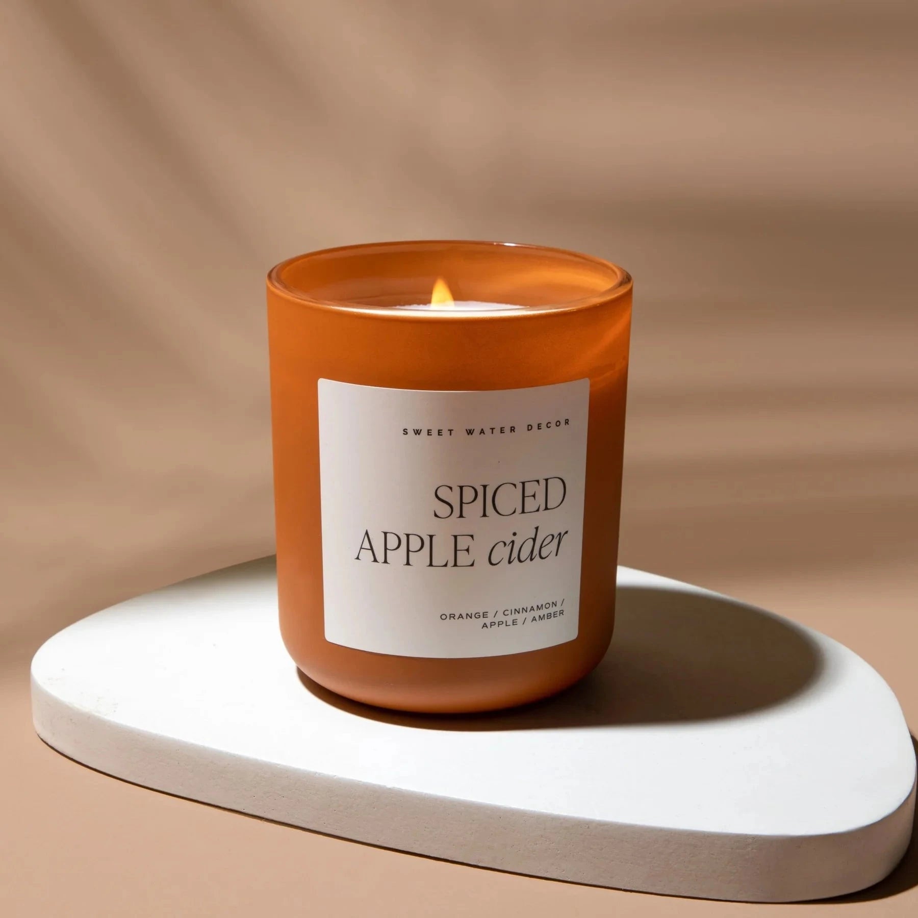 Brennende Spiced Apple Rider Sojawachskerze von Sweet Water Decor auf Natursteinplatte