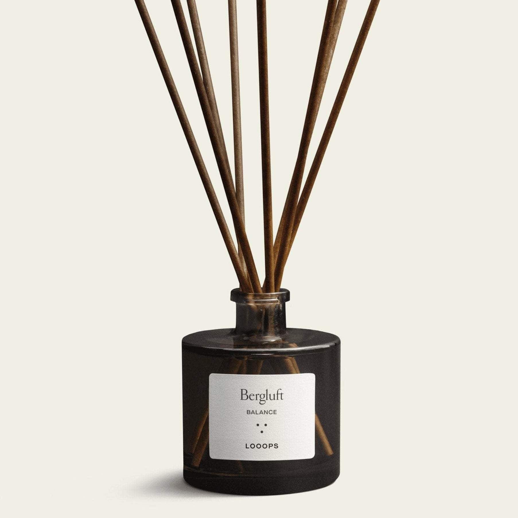 Duftstäbchen stecken in der Raumduft Glasflasche Bergluft von Looops, die vor weißem Hintergrund steht.