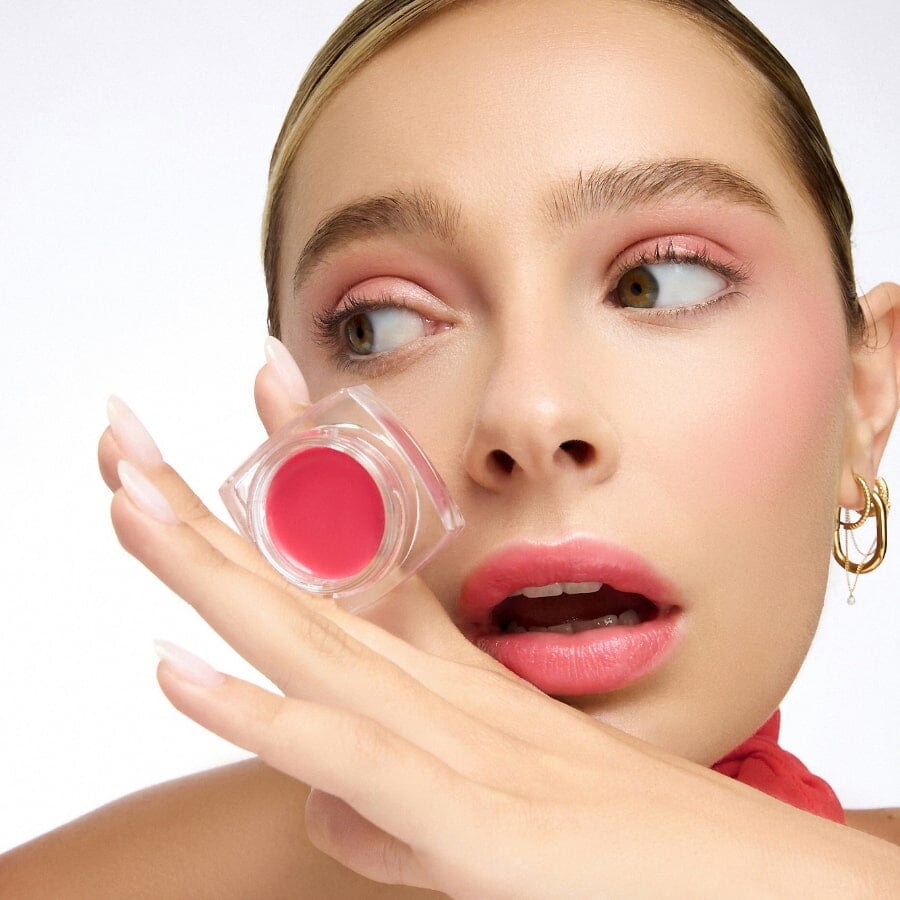 Frau hält Lpbalm VANNINA von Le Rouge Francais mit der Handrückseite vor ihr Gesicht.