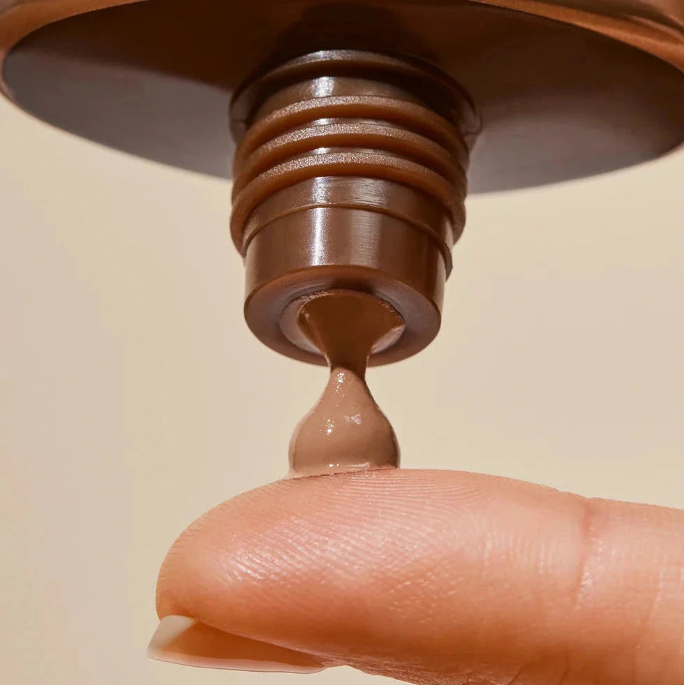 Inika Tinted Natural Sunscreen SPF50+ wird auf einen Finger getropft.