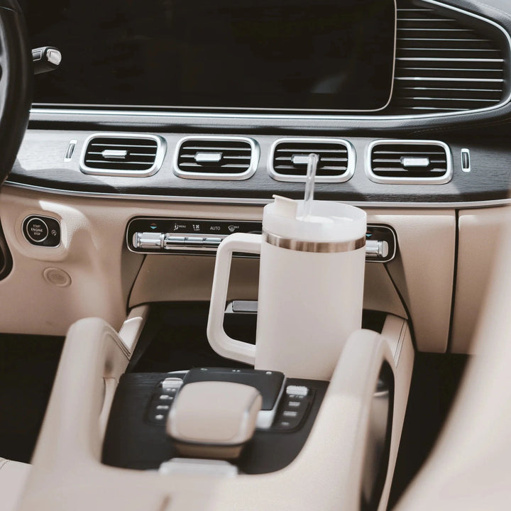 Cremefarbener Tumbler / Thermobecher von Sweet Water Decor steht in der Mittelkonsole eines Autos.