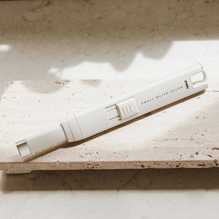 Weißes USB rechargable Feuerzeuge SWEET WATER DECOR liegt auf einer Steinplatte.