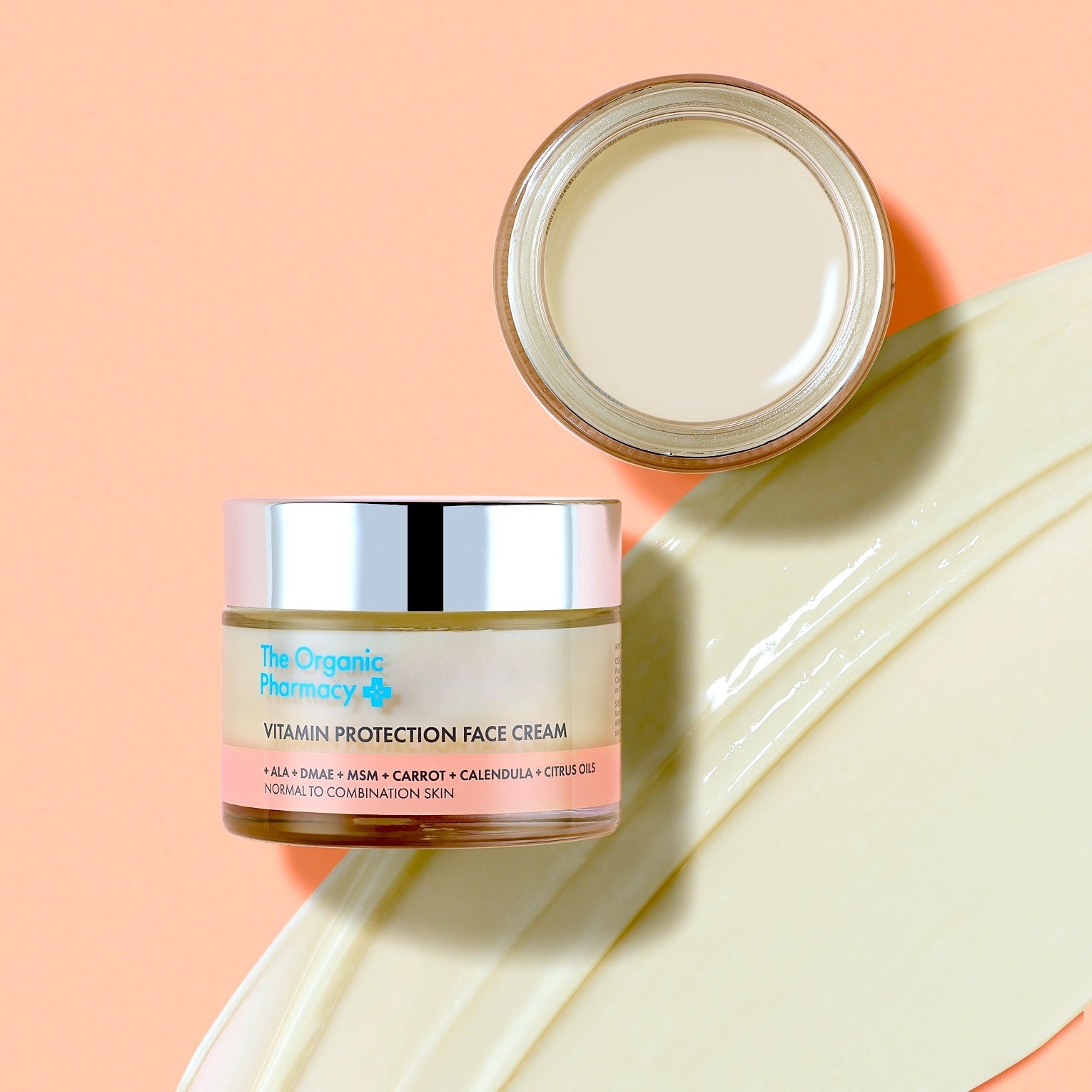 Die Vitamin C Creme von The Organic Pharmacy auf einer Abbildung ihrer Textur vor orangenem Hintergrund