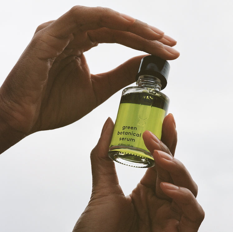 ACTIVIST Green Botanical Serum Flasche wird von weiblichen Händen präsentiert North Glow