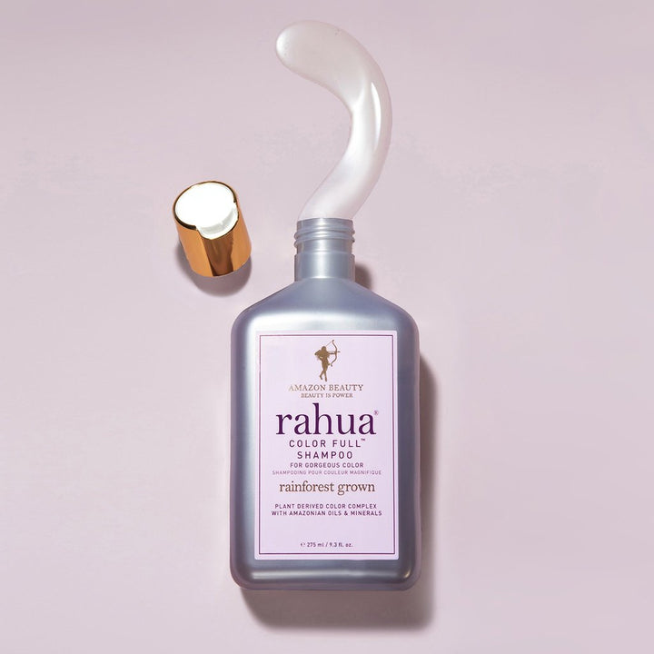 Offene Rahua Color Full Shampoo Flasche mit Texturbeispiel auf rosafarbenem Hintergrund.