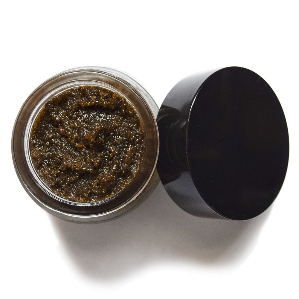 Aus der Vogelperspektive sieht man ein offenes UMA Absolute Anti Aging Body Scrub Schraubglas mir einer körnigen, braunen Masse.