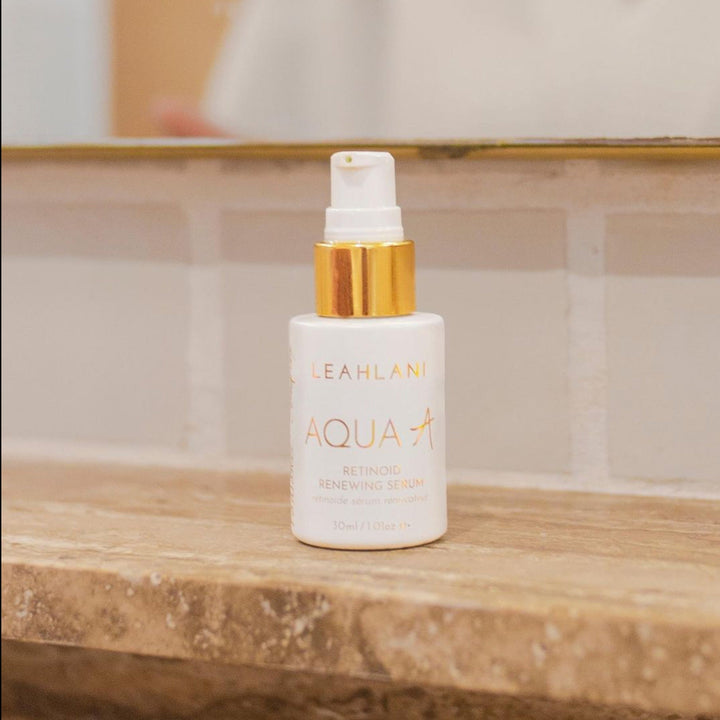 Leahlani Retinol AquaA weiße Flasche  auf Holzbrett vor hellen Fliesen und Badspiegel