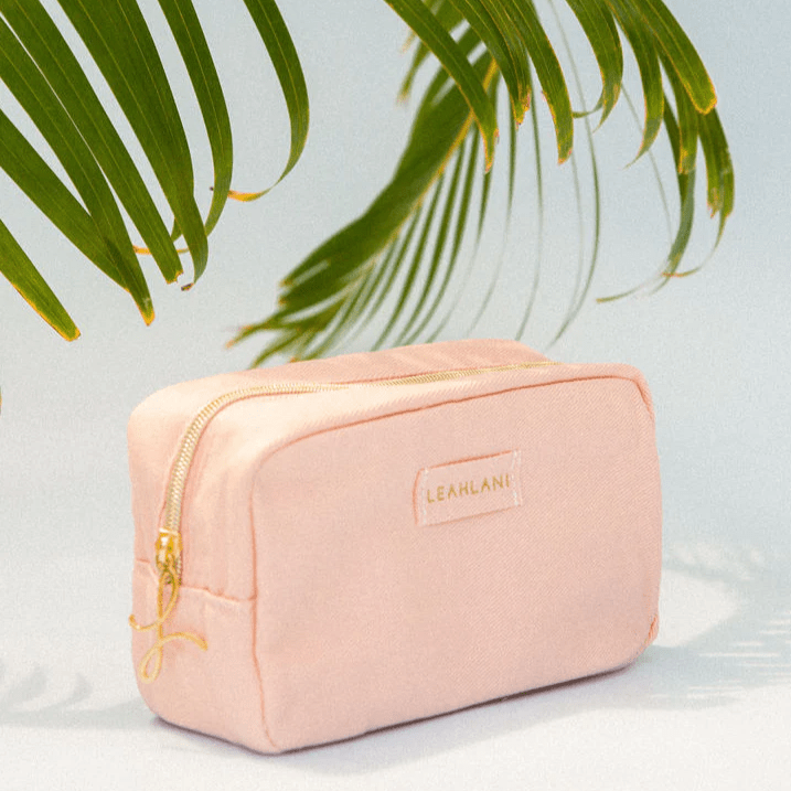 Leahlani Beauty Bag vor weißem Hintergrund mit grünen Palmenblättern