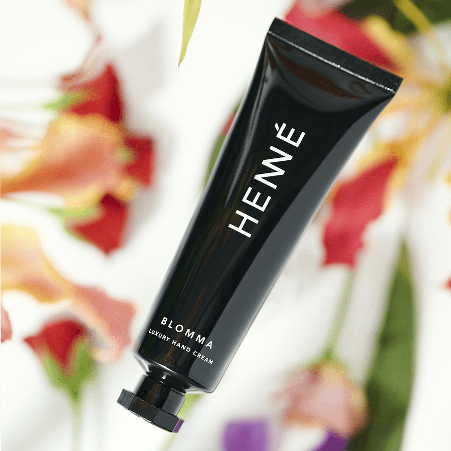 Schwarze Tube Henné Handcreme Blomma vor verschwommenen Blumen.