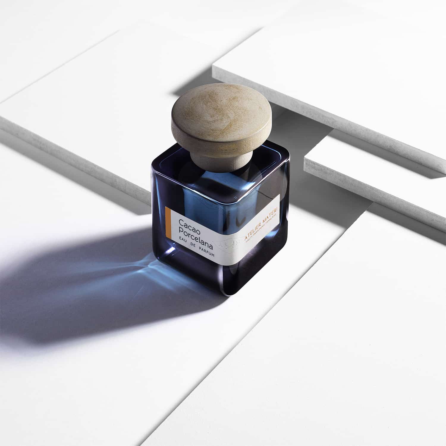 Dunkelblaue Glasflasche mit grsuem Deckel "Cacao Porcelana" von Atelier Materi stehen auf einer weißem Fläche.