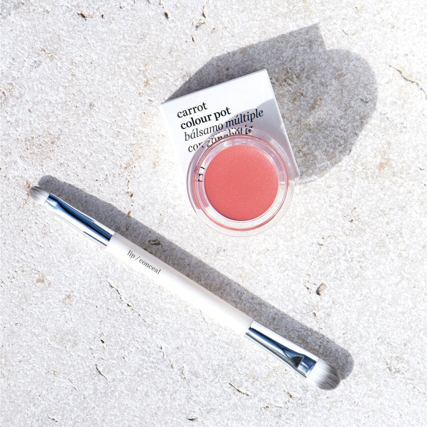 Ere Perez Carrot Colour Pots offener Tiegel mit angelehntem Deckel und doppel-seitigem Pinsel auf weißem Untergrund.