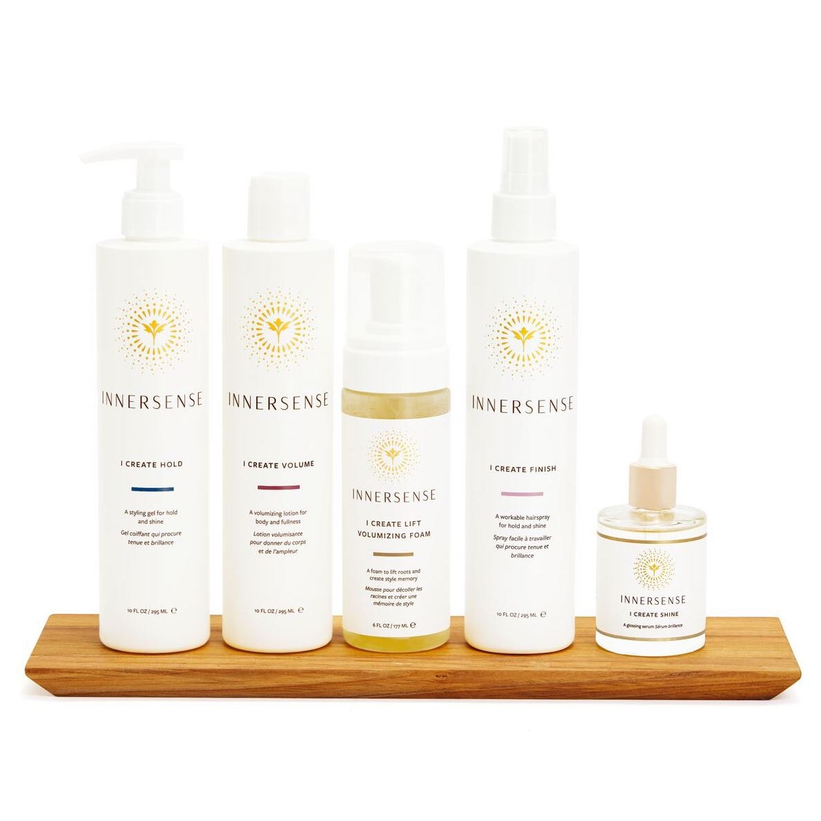 5 Produkte der Innersense I Create Shine Serie stehen auf einem Holzbrett vor weißem Hingtergrund.