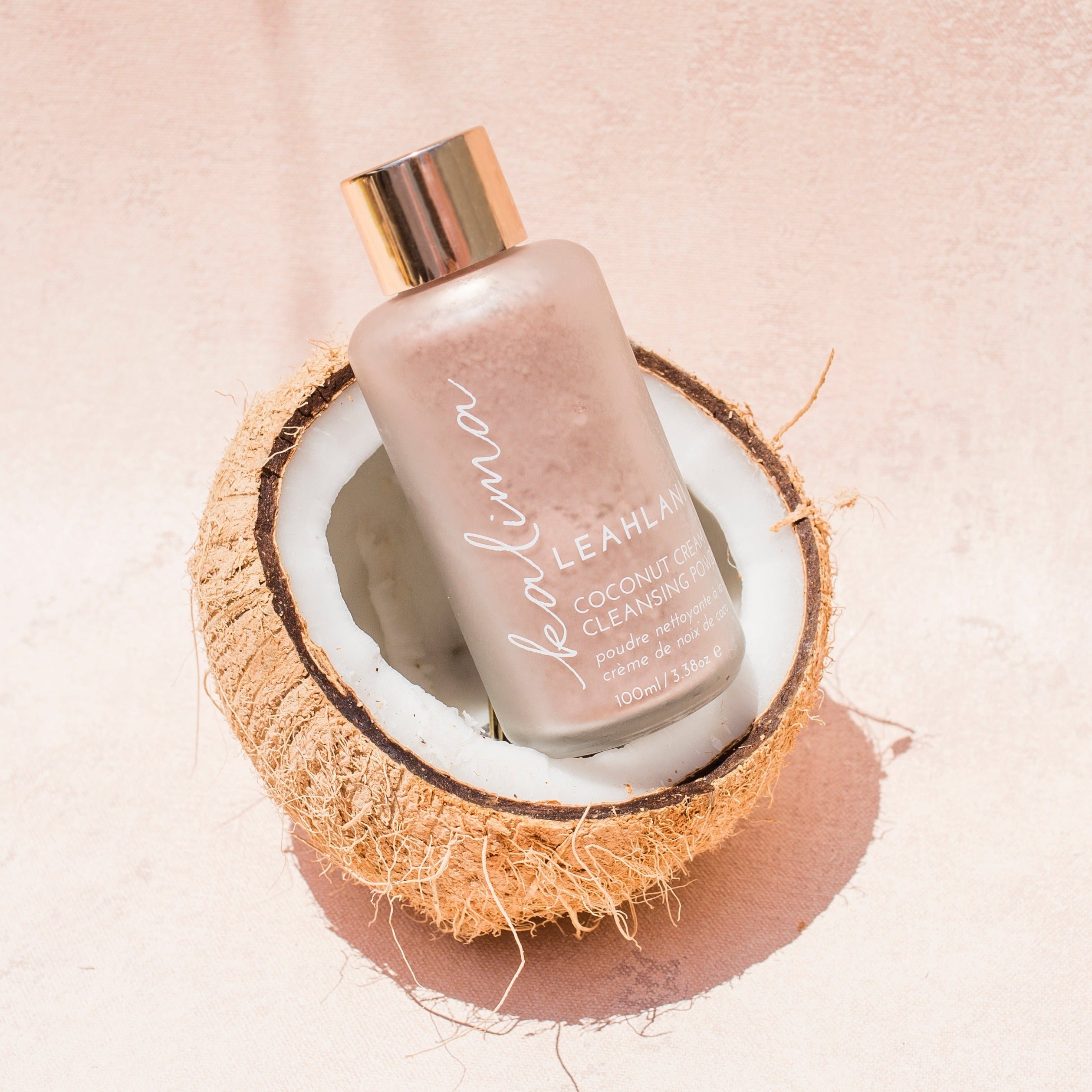 Kalima Coconut Cream Powder von Leahlani – Reinigungspulver in edler Glasverpackung liegt in einer halben Kokosnuss